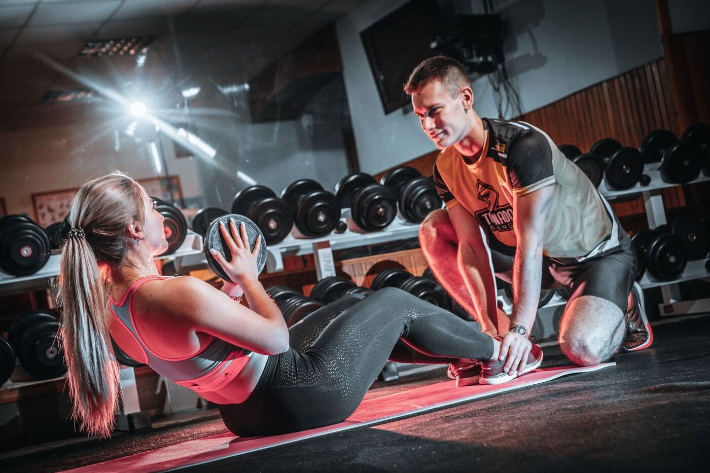 Entrenador personal asistiendo a una socia durante un ejercicio de abdominales