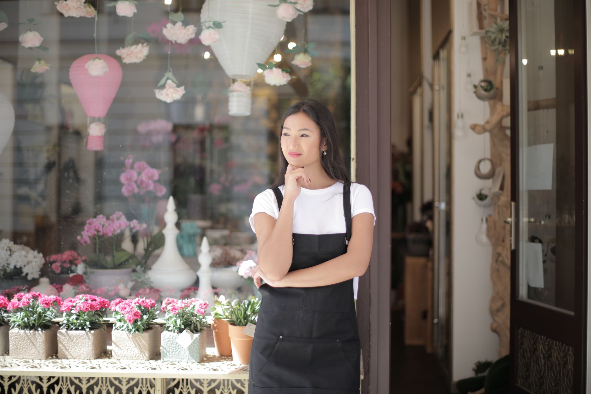Dueña de una tienda parada frente a su local con flores y plantas en el escaparate